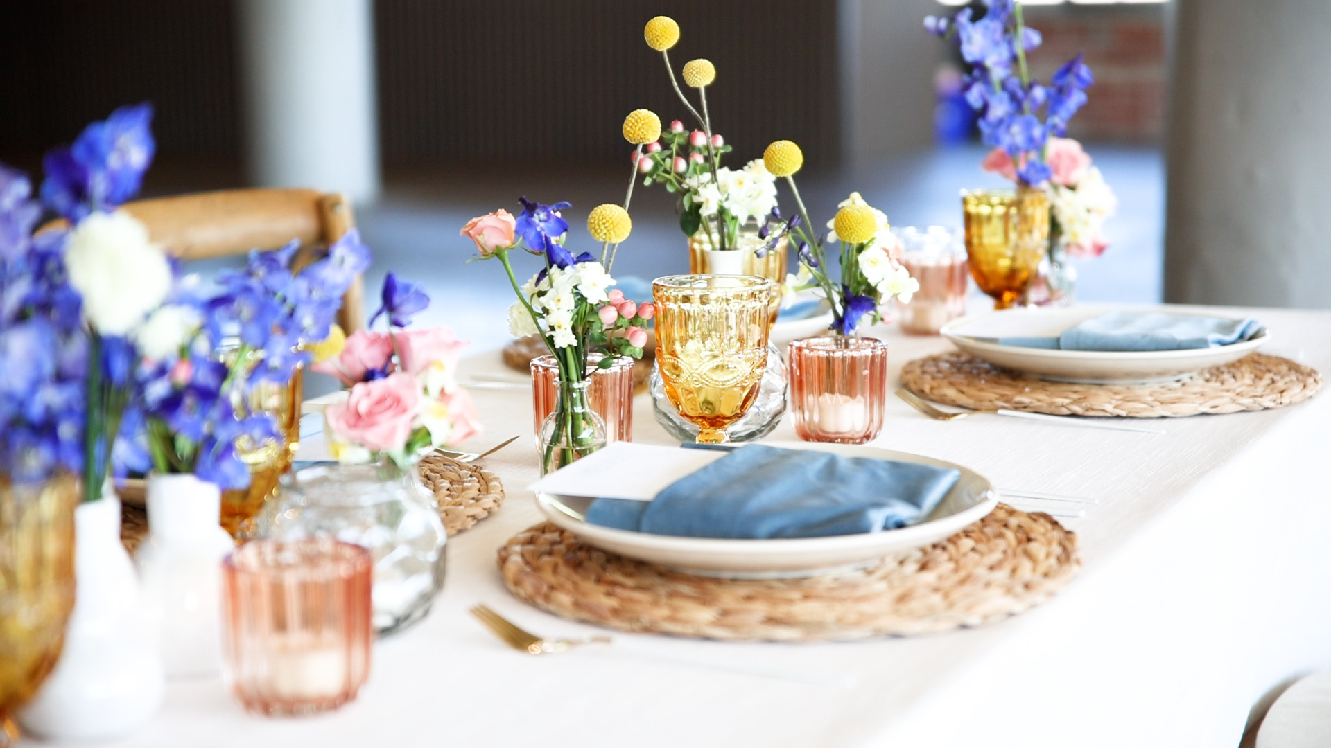 Table setting details with blue flowers and napkins on a white table cloth
