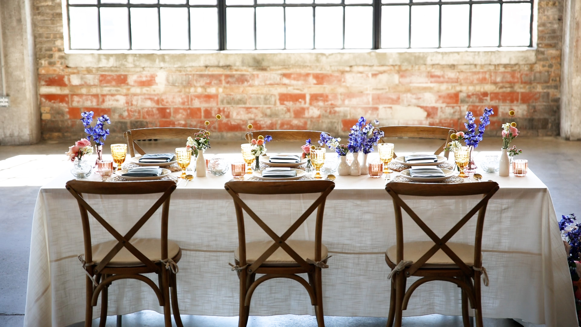 A table setting with blue flowers in front of a window in a brick wall in one of the best minneapolis wedding venues